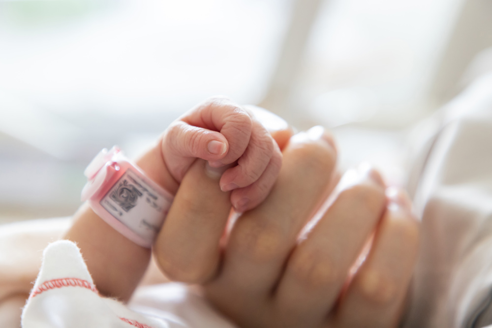 Baby holding onto adult finger