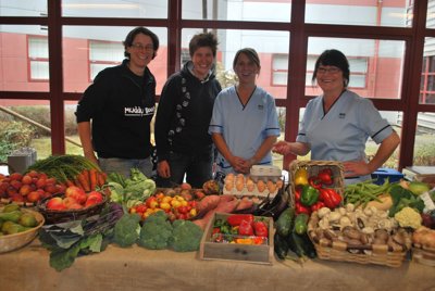 people standing behind table full of fruit and vegetables